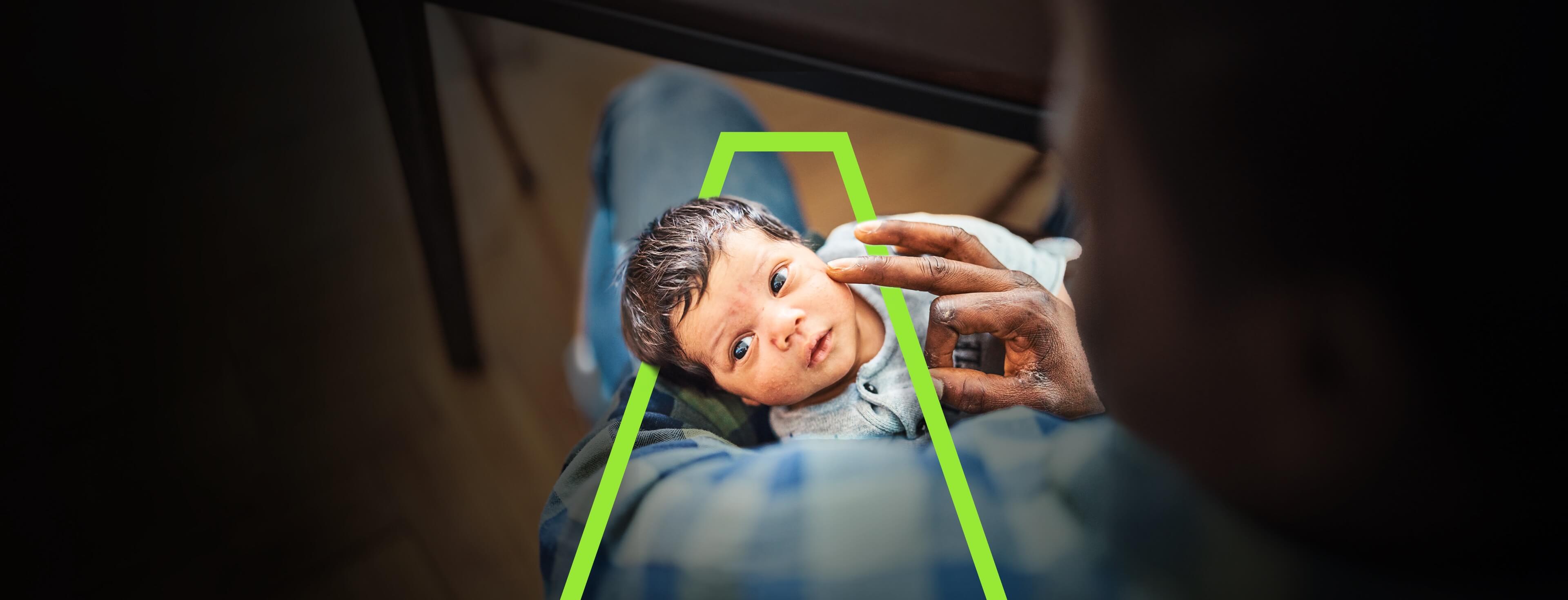 A father delicately touching the face of his newborn baby