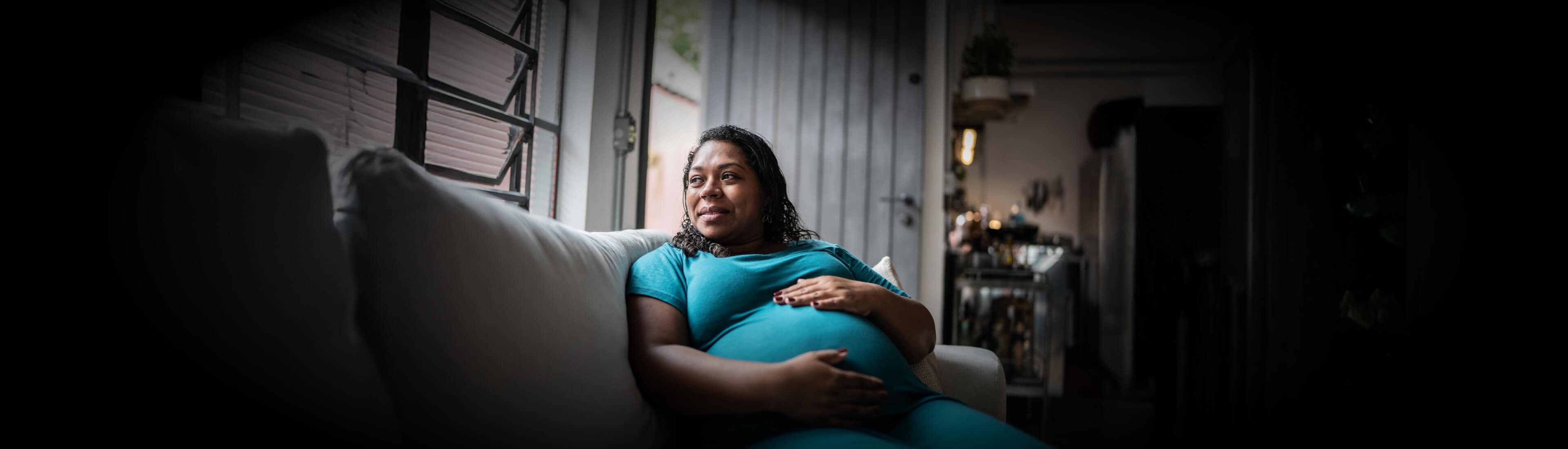 A heavily pregnant woman relaxing on a couch
